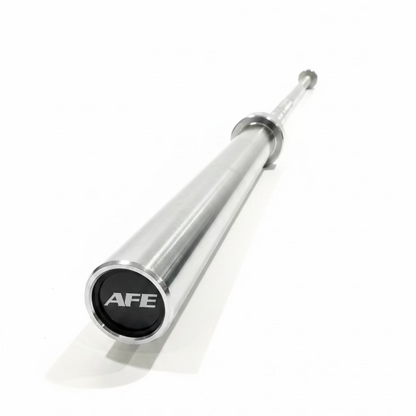 A chrome steel weightlifting barbell with a black end cap featuring the white 'AFE' logo, resting on a black rubber gym floor with weight plates and racks visible in the background.