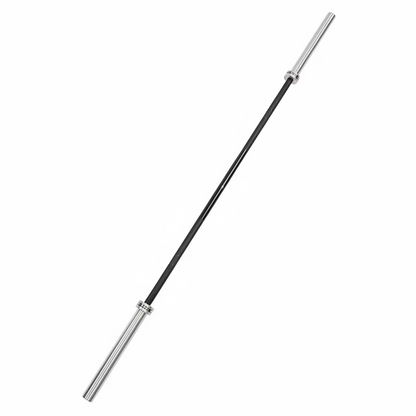 A silver metal barbell with black weight plates lies on dark gray gym floor tiles, with other gym equipment partially visible in the background.