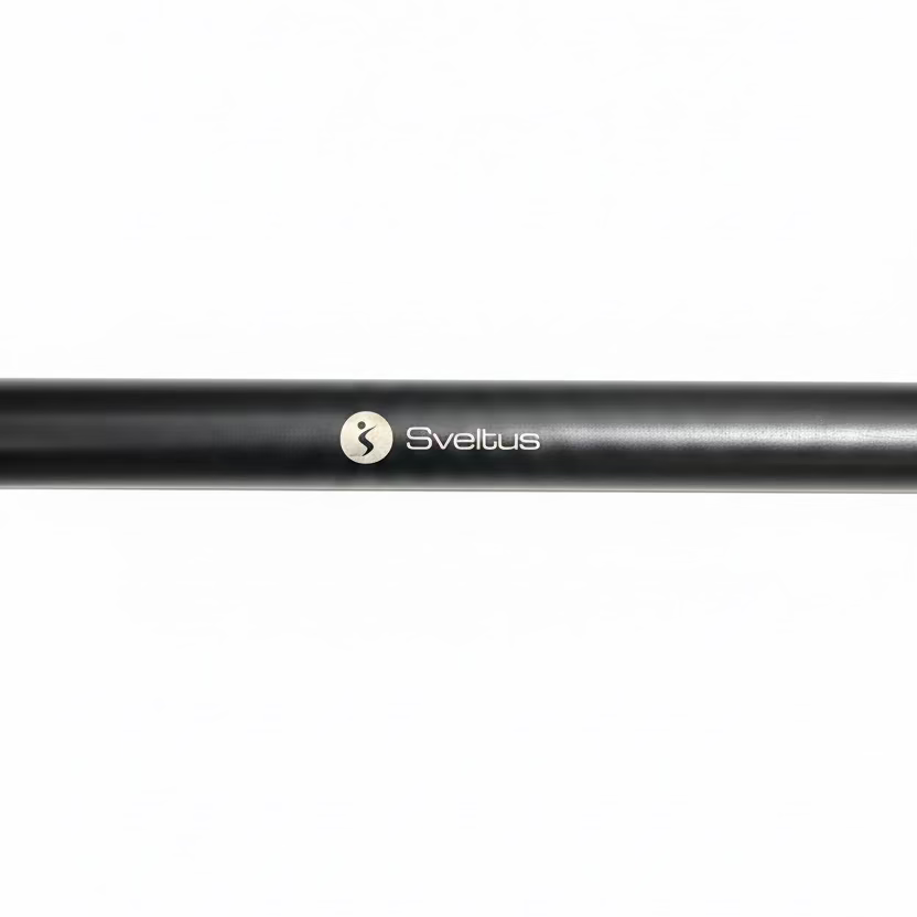 A close-up of a black metal bar with the Sveltus logo printed in white, resting on a dark speckled gym floor.