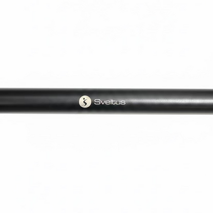 A close-up of a black metal bar with the Sveltus logo printed in white, resting on a dark speckled gym floor.