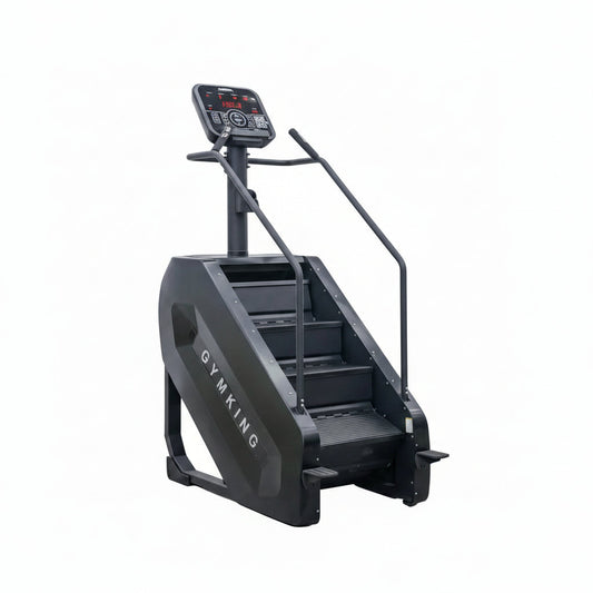A black stair climber exercise machine with a digital display screen and handrails, positioned against a plain light gray wall and concrete floor.