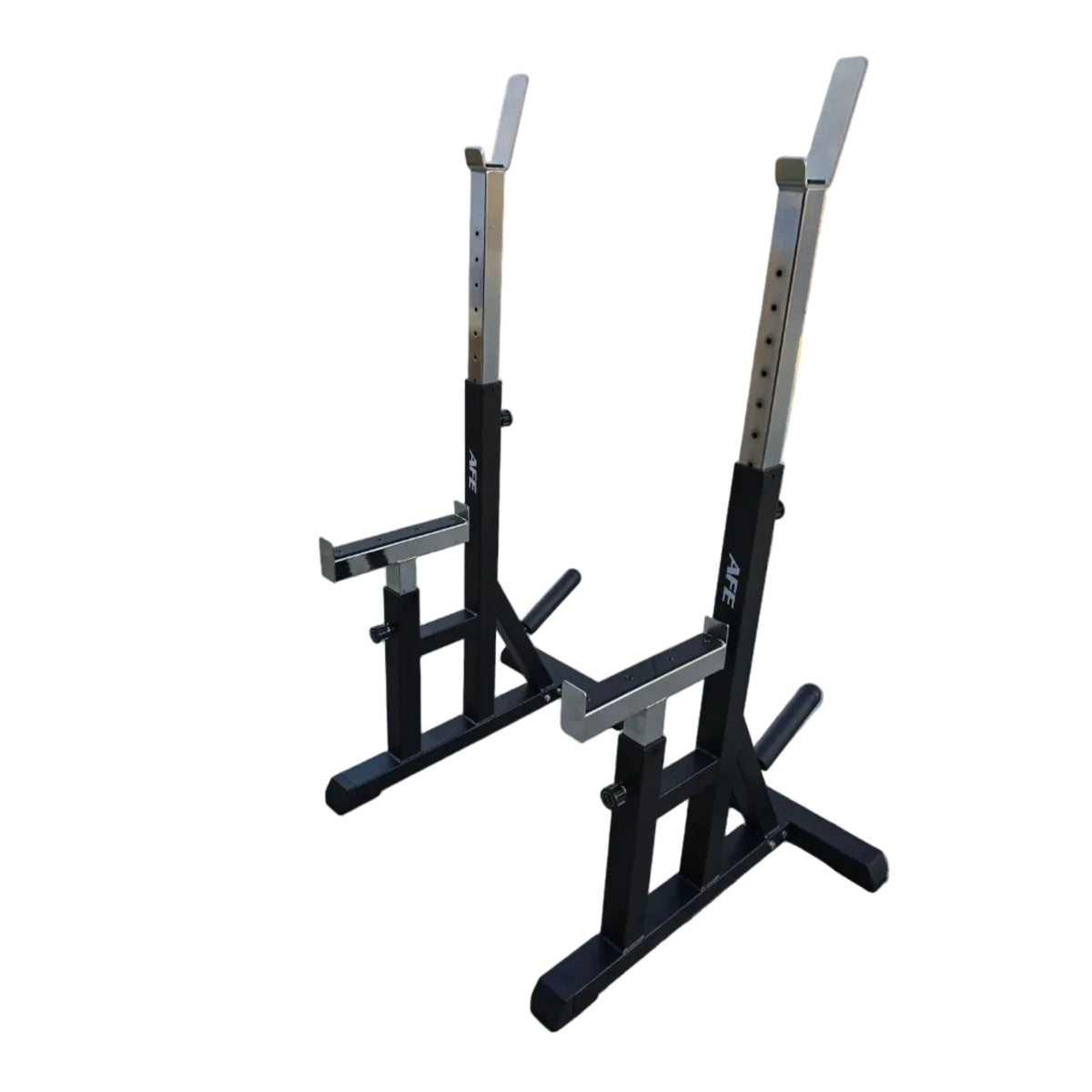 A pair of black and silver AEX power racks with safety arms, positioned on a concrete surface in front of a building with a white garage door.