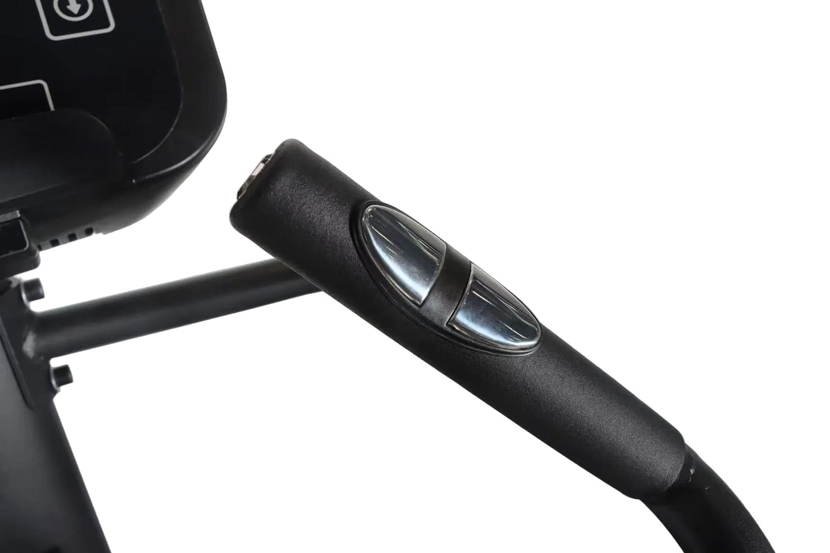 Close-up of a black treadmill handlebar with a glossy silver oval control button, showing part of the treadmill console on the left against a light gray background.