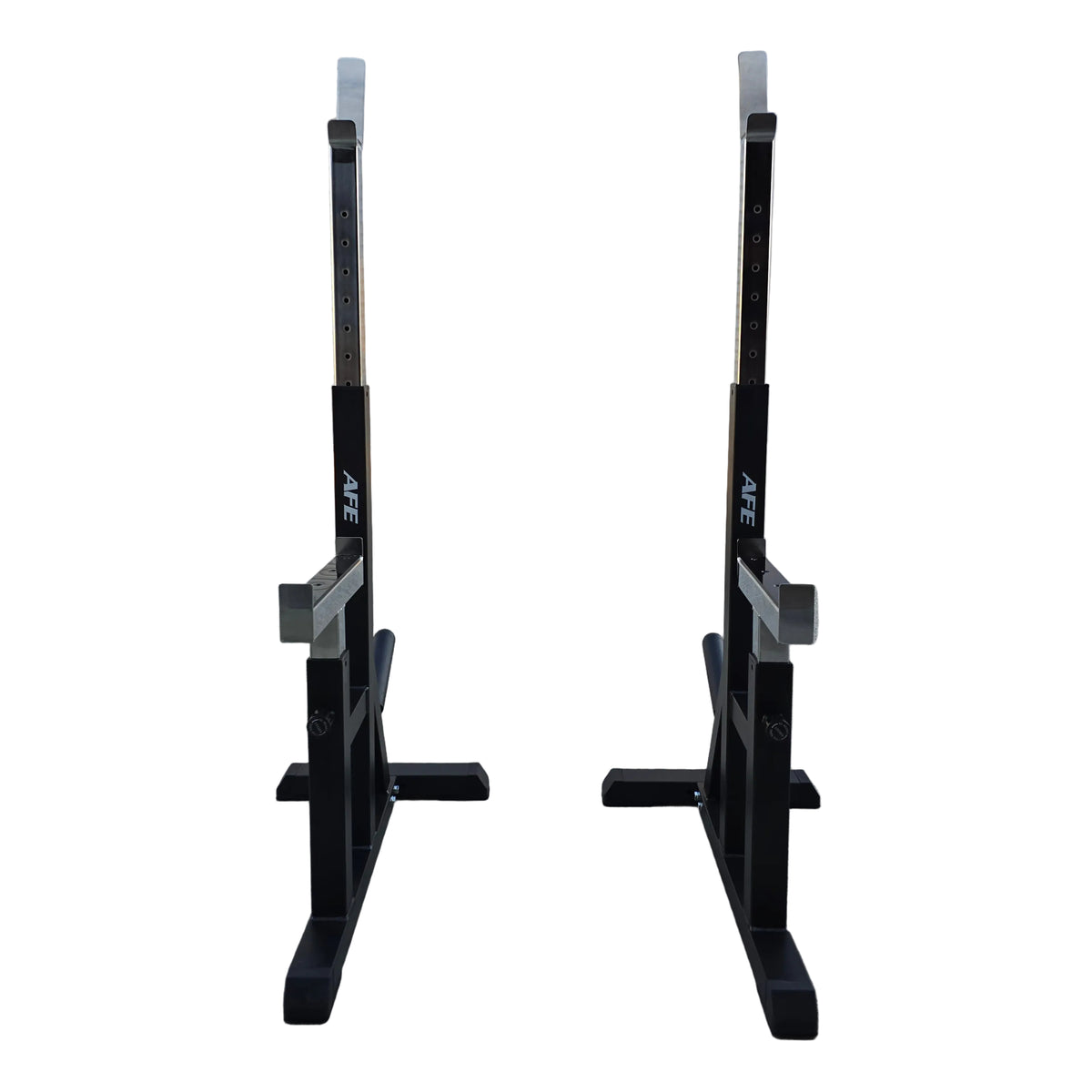 Two black adjustable squat racks with white measurement markings, positioned side-by-side on a concrete floor in front of a white garage door.