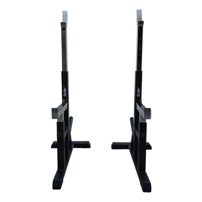 Two black adjustable squat racks with white measurement markings, positioned side-by-side on a concrete floor in front of a white garage door.