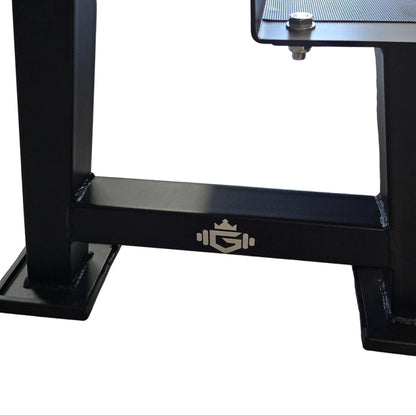 A black adjustable standing desk with a glass top and metal frame, shown in a gym setting on a wood-look floor.