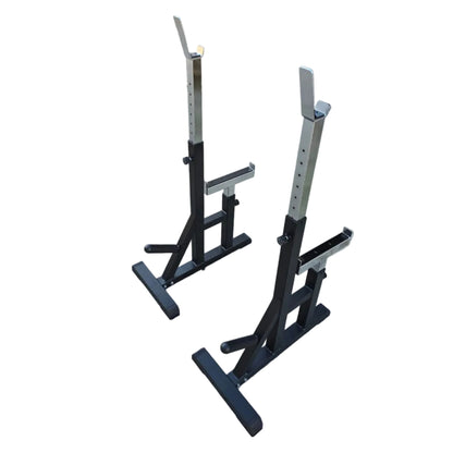 Two black and silver weight squat racks standing on a concrete floor in front of a warehouse or garage door.