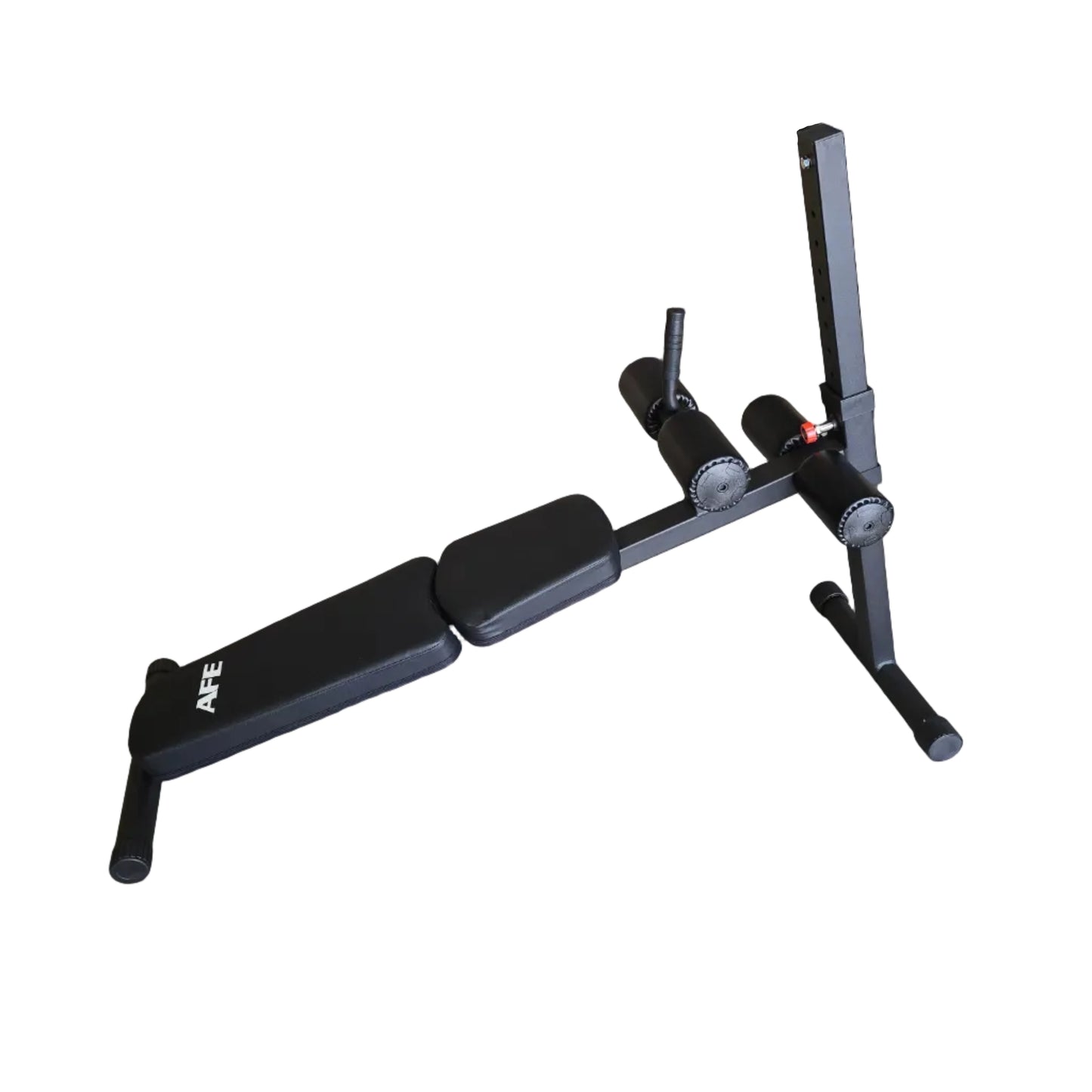 A black adjustable weight bench with a footrest and leg rest, photographed in a warehouse setting with cardboard boxes and shelving in the background.
