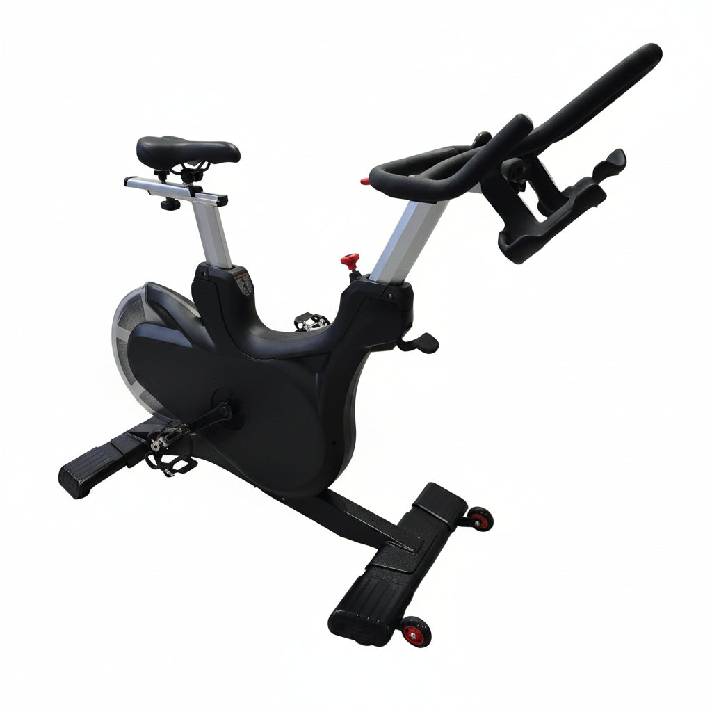 A black and silver indoor stationary exercise bike with a padded seat and adjustable handlebars, photographed on a light wood floor in front of a draped white fabric backdrop.